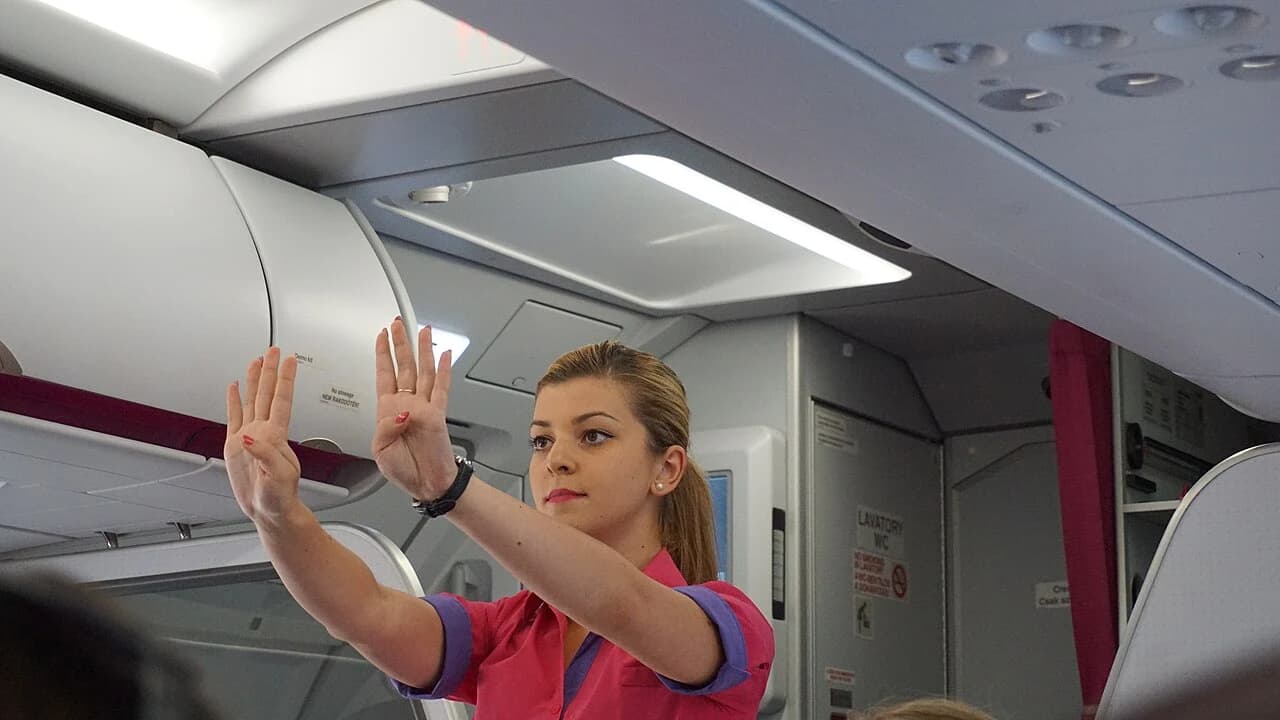 Flight attendant demonstrating safety procedures in an aircraft cabin